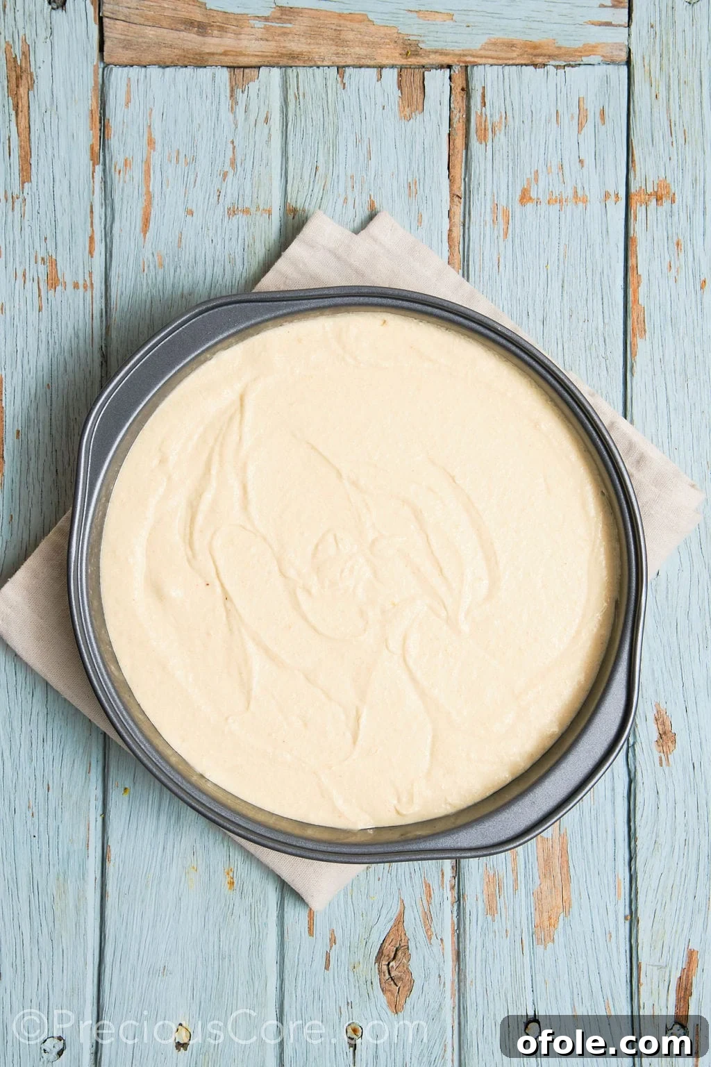 The smooth, ready-to-bake cake batter for the almond and pear cake evenly spread within a prepared round cake pan.