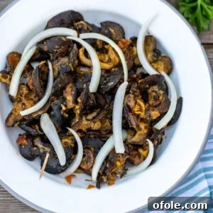 Savoring Cameroon's Snail Delicacy 5 Cameroonian snails on a white plate topped with sliced onions, a delicious African delicacy.