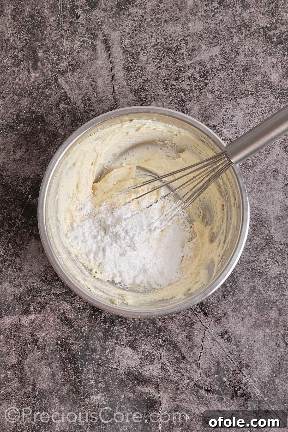Powdered sugar being added to the beaten cream cheese and butter mixture, to be mixed until creamy and smooth.