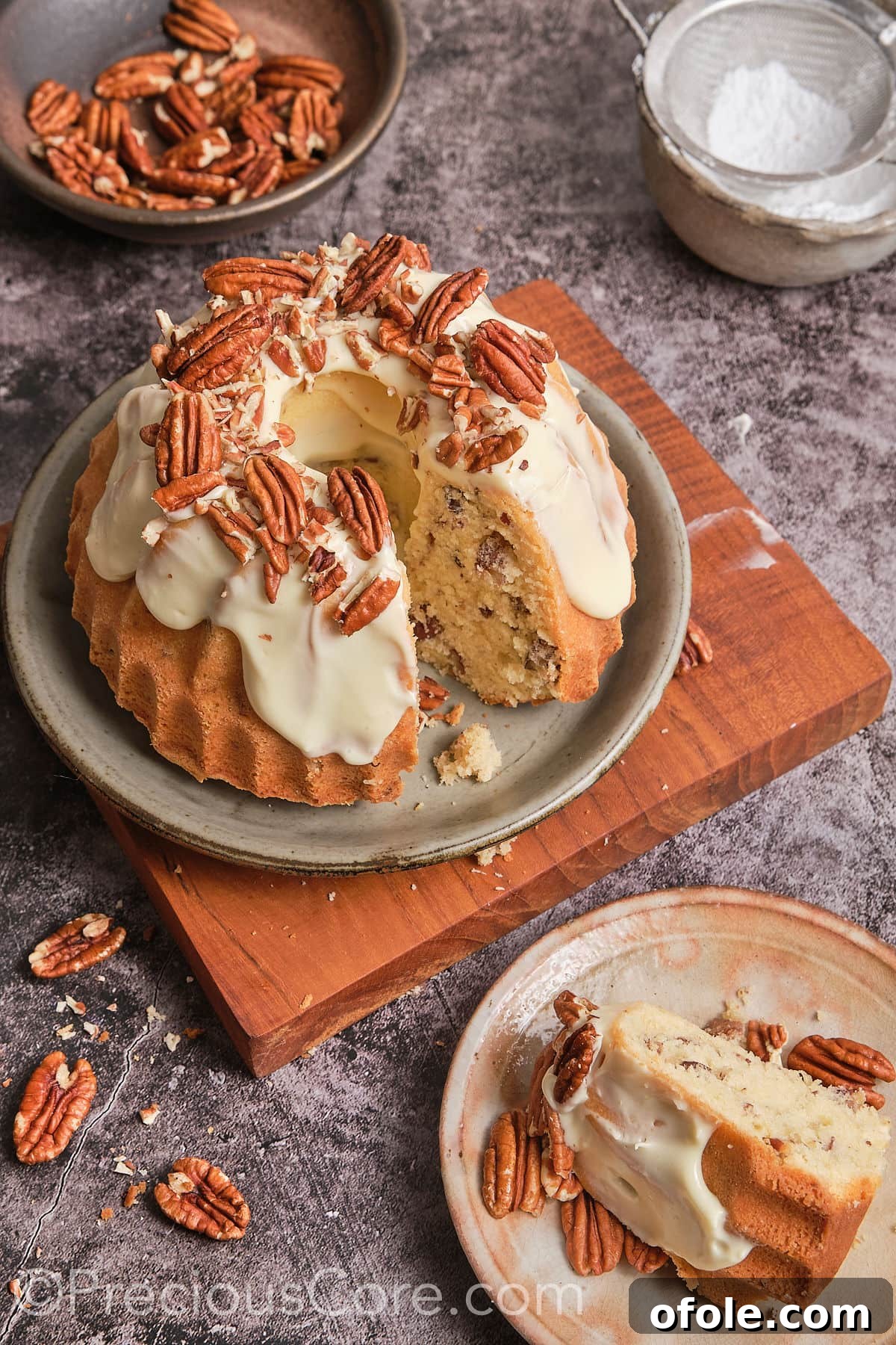 A close-up shot of a slice taken out of the Butter Pecan Pound Cake, showing the moist cake texture, pecans, and thick cream cheese frosting.