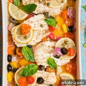 White fish fillets in a casserole dish baked with veggies.