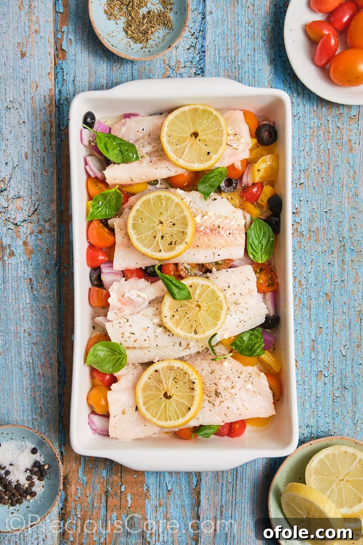 Vibrant Mediterranean Baked Fish 8 Baking dish filled with chopped veggies, marinated fish and lemon slices.