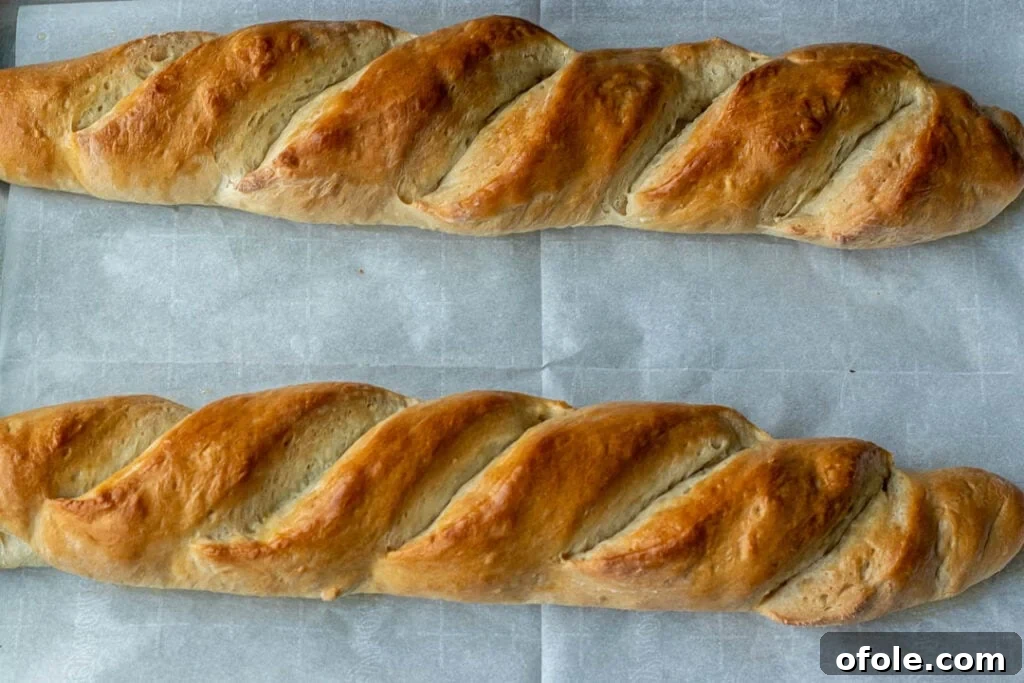 Effortless Crusty French Loaves 3 Freshly baked homemade French bread cooling on a baking sheet, steam gently rising