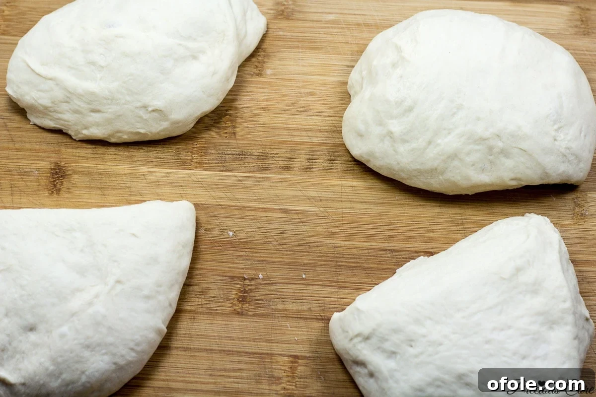 Effortless Crusty French Loaves 7 French bread dough neatly cut into four equal pieces on a wooden board