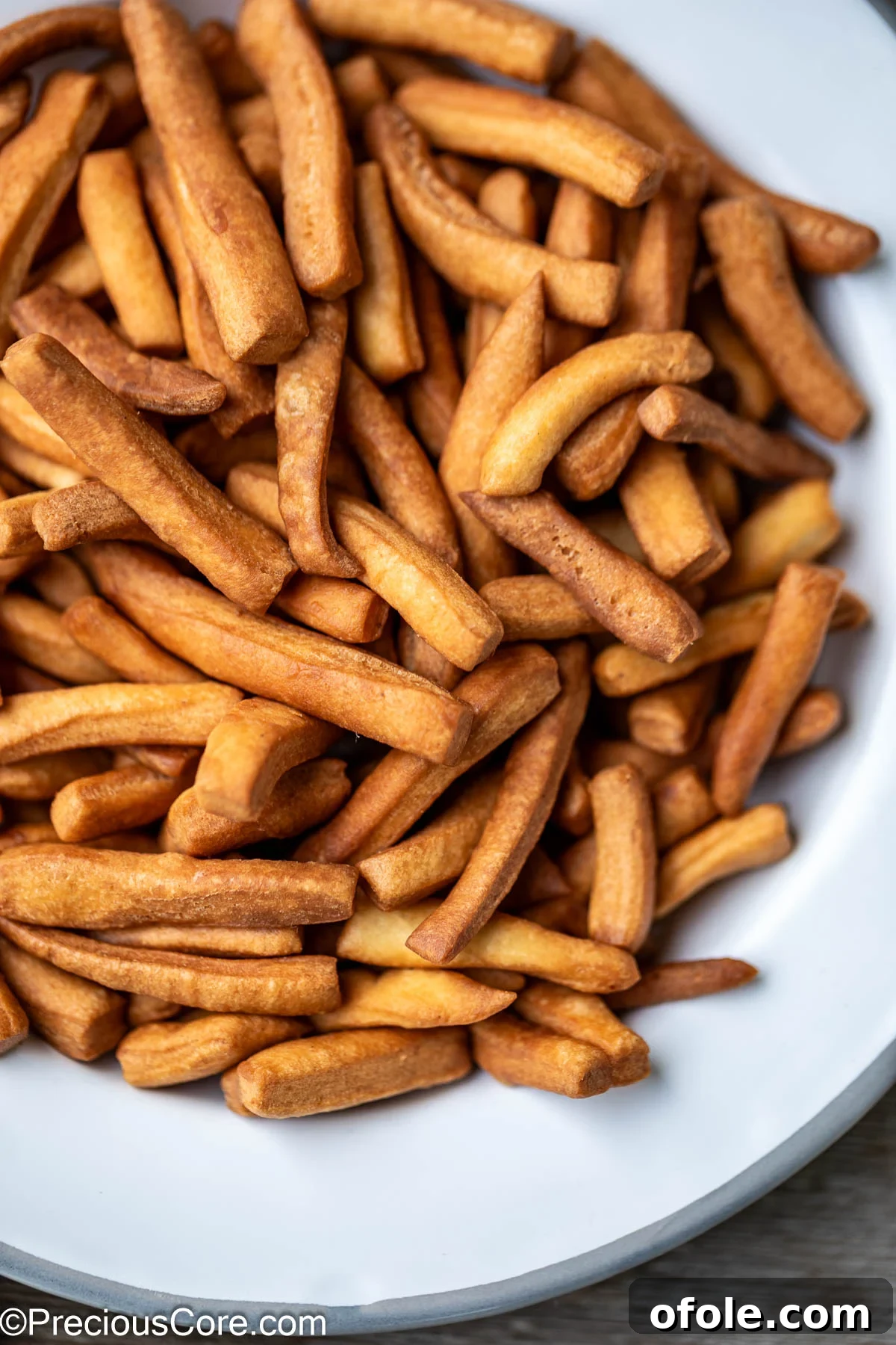 A close-up view of perfectly fried Chin Chin pieces arranged on a white plate, showcasing their inviting texture.