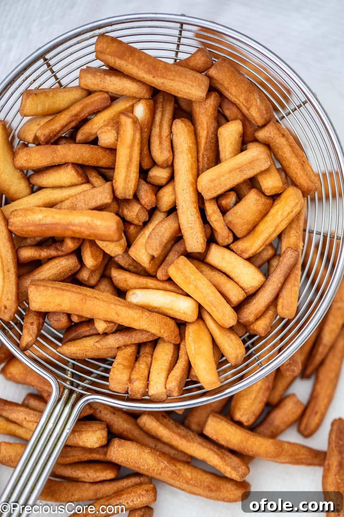 Golden brown, crunchy Chin Chin pieces resting in a metal frying spoon.