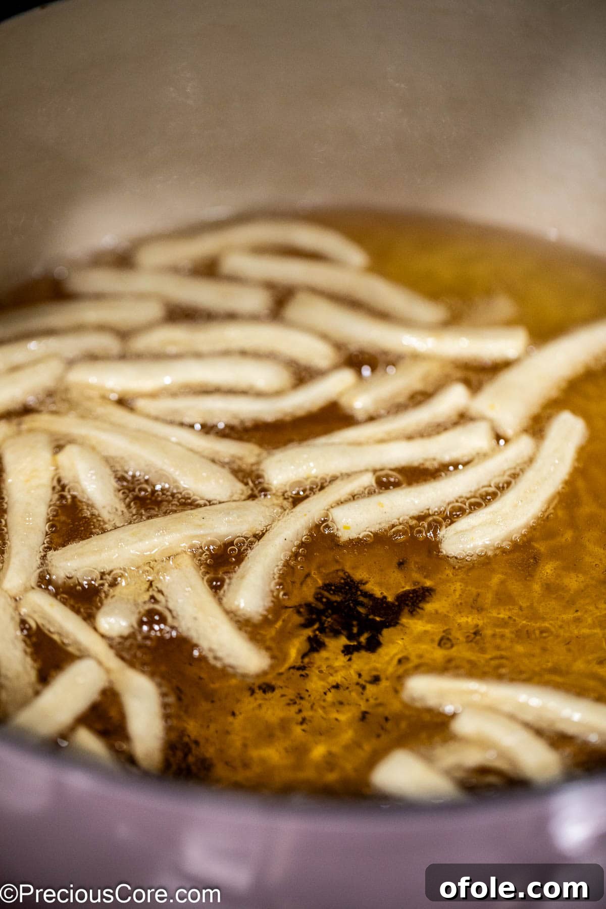 Dough strips bubbling and frying in hot oil, turning golden.