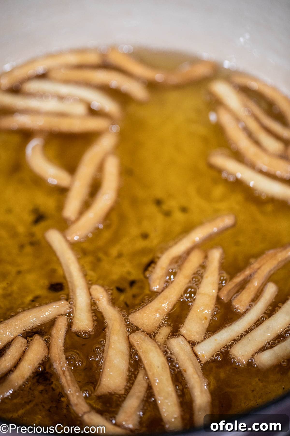 Perfectly browned Chin Chin pieces frying in oil, indicating they are almost done.