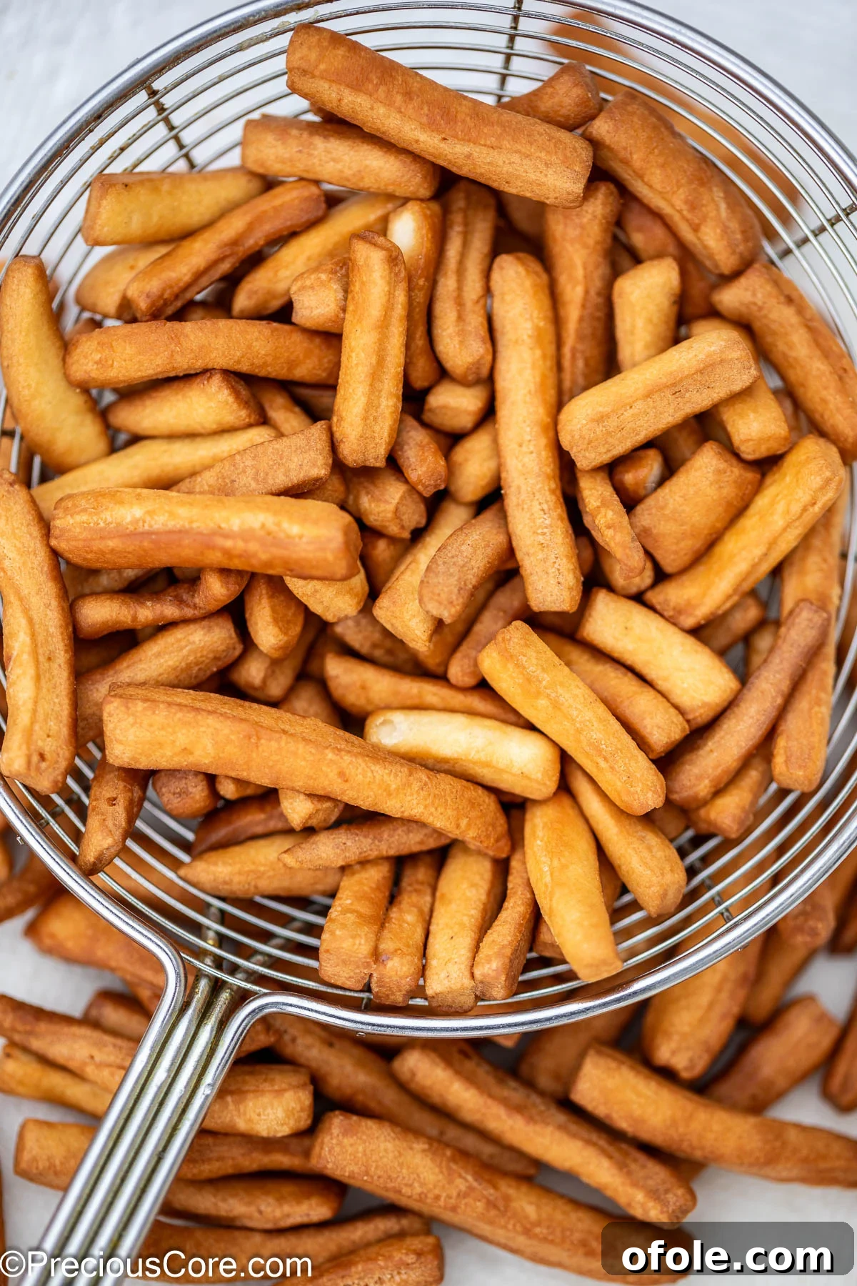 Freshly fried, golden brown Chin Chin scooped out of oil with a slotted spoon.
