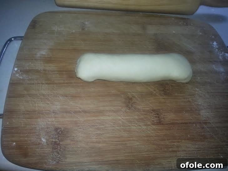 Folding Edges of Milk Bread Dough Edges of the rolled dough log being folded inwards.