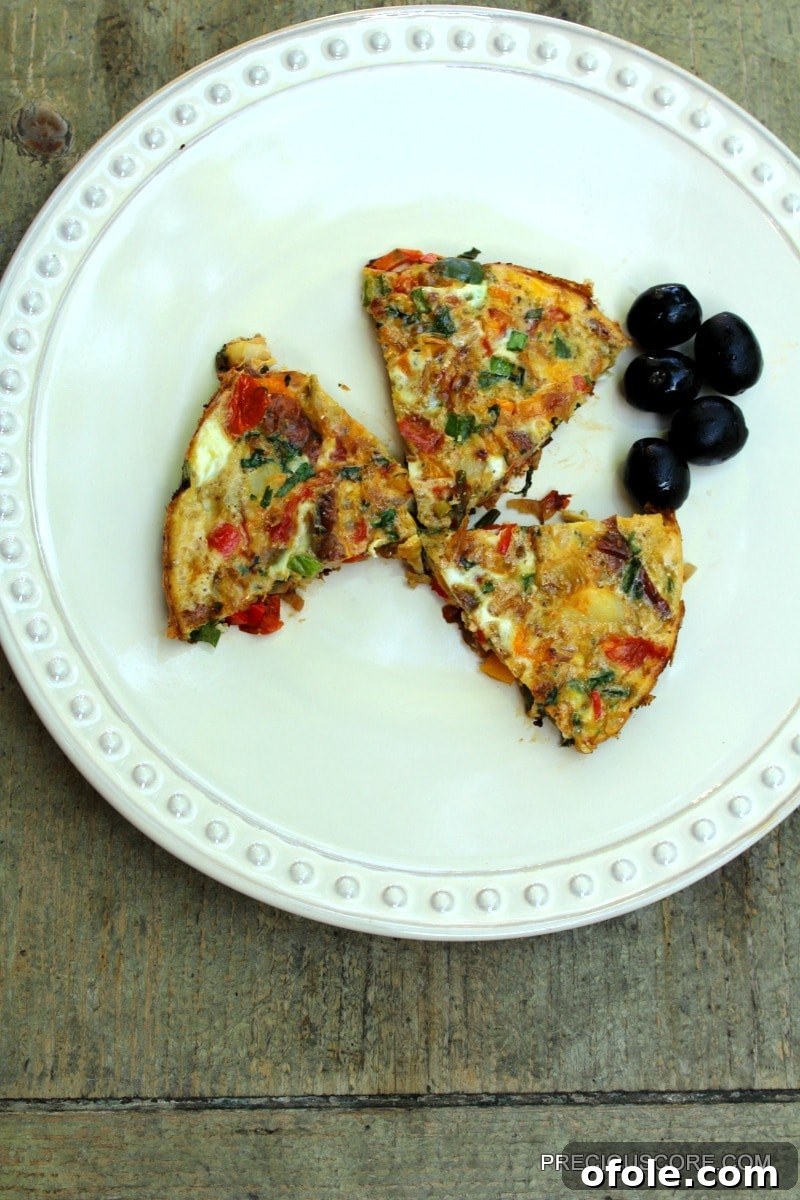 Hearty Breakfast Frittata 3 A slice of frittata served with pitted olives on a white plate