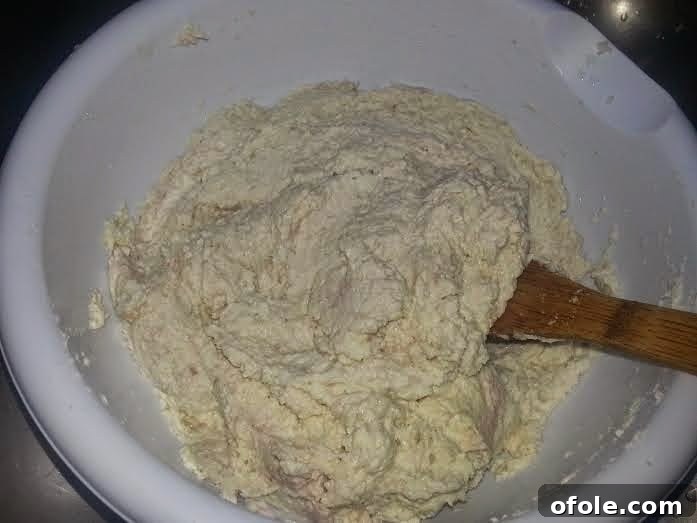 Warm palm oil being added to the cocoyam mixture, enhancing color and flavor.