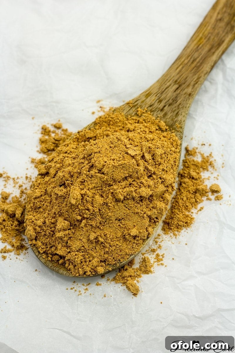Suya spice on a wooden spoon, showcasing its rich texture and color.