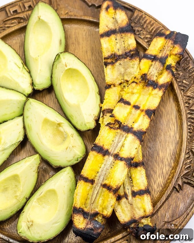 A plate featuring beautifully grilled plantains served alongside fresh avocado wedges, highlighting a healthy and delicious meal.