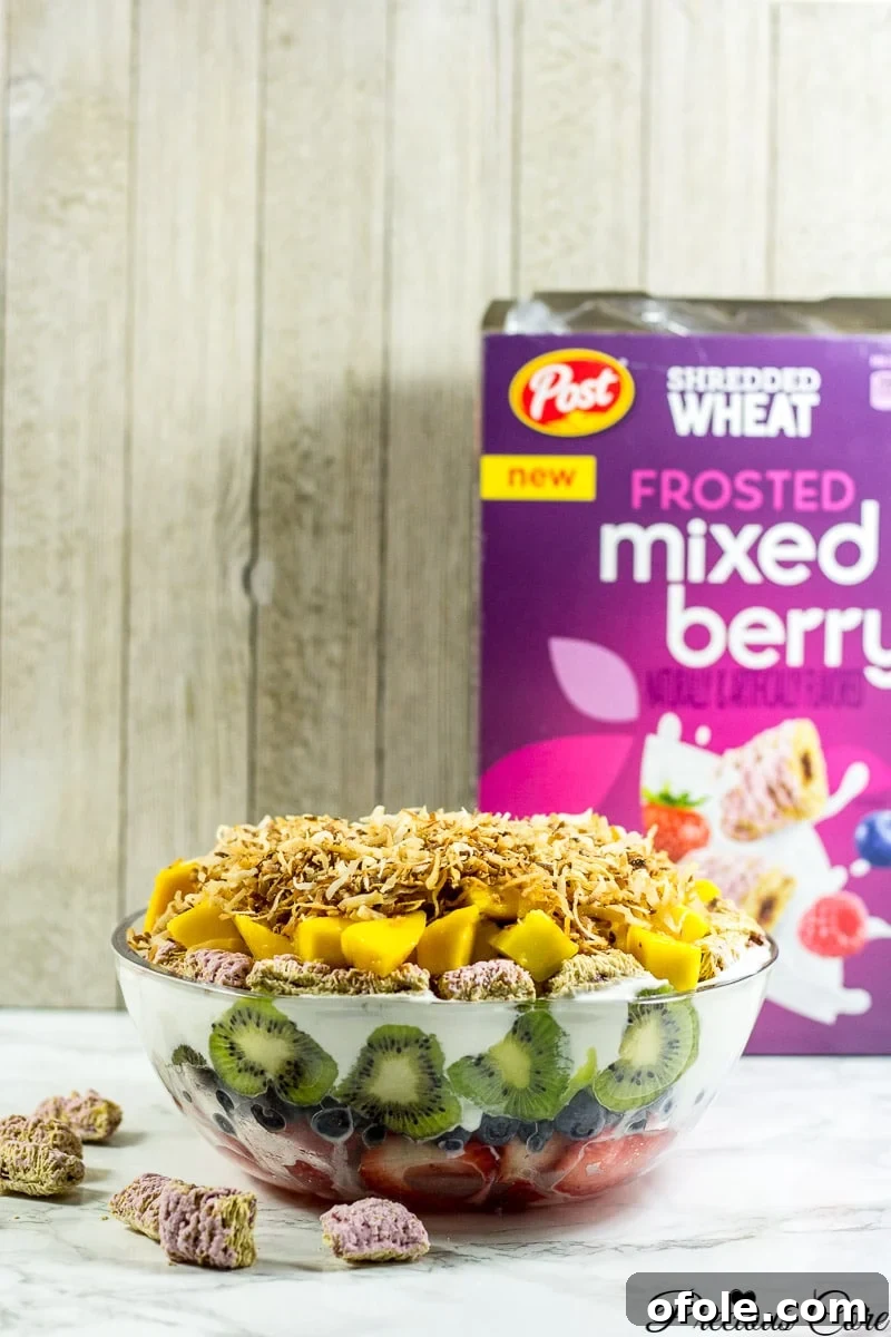 Vibrant Seven Layer Fruit Stack 2 Seven layer fruit salad with a box of Frosted mixed berry Shredded Wheat, showcasing a healthy and vibrant breakfast or snack idea.