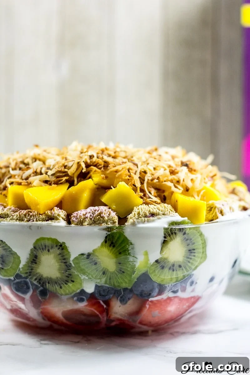 Rainbow Fruit Delight 3 A stunning 7-layer fruit salad presented in a clear glass bowl, showcasing vibrant layers of fresh fruit and creamy yogurt.