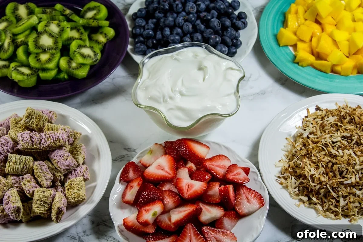 Rainbow Fruit Delight 7 A vibrant selection of fresh ingredients including strawberries, blueberries, kiwi, mango, toasted coconut flakes, Greek yogurt, and Post Shredded Wheat Mixed Berry cereal, ready for assembly.