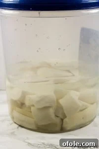 Cassava roots soaking in water in a large container, undergoing the fermentation process for making fufu.
