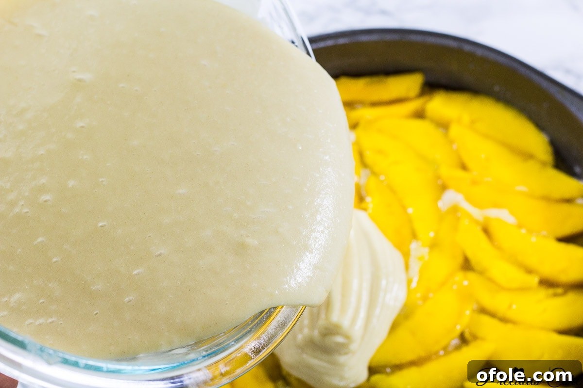 Caramelized Mango Flip-Over Cake 6 Cake batter being poured over the beautifully arranged mango slices in the pan