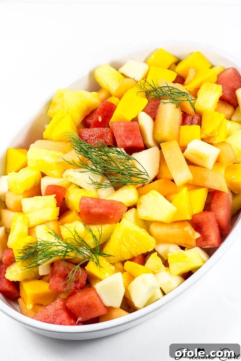 Vibrant Cameroonian Fruit Salad How To 2 A large serving bowl filled with vibrant Cameroonian fruit salad, featuring visible pieces of watermelon, mango, pineapple, and apple.