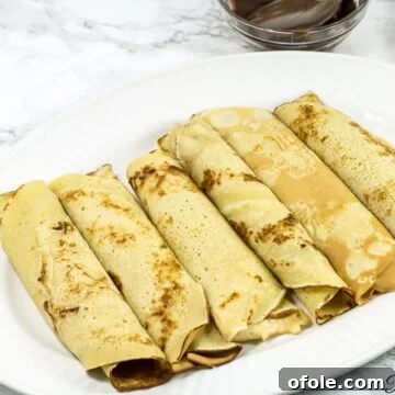 Cameroon's Delightful Savory Pancakes 5 Cameroonian pancakes rolled on a white plate.