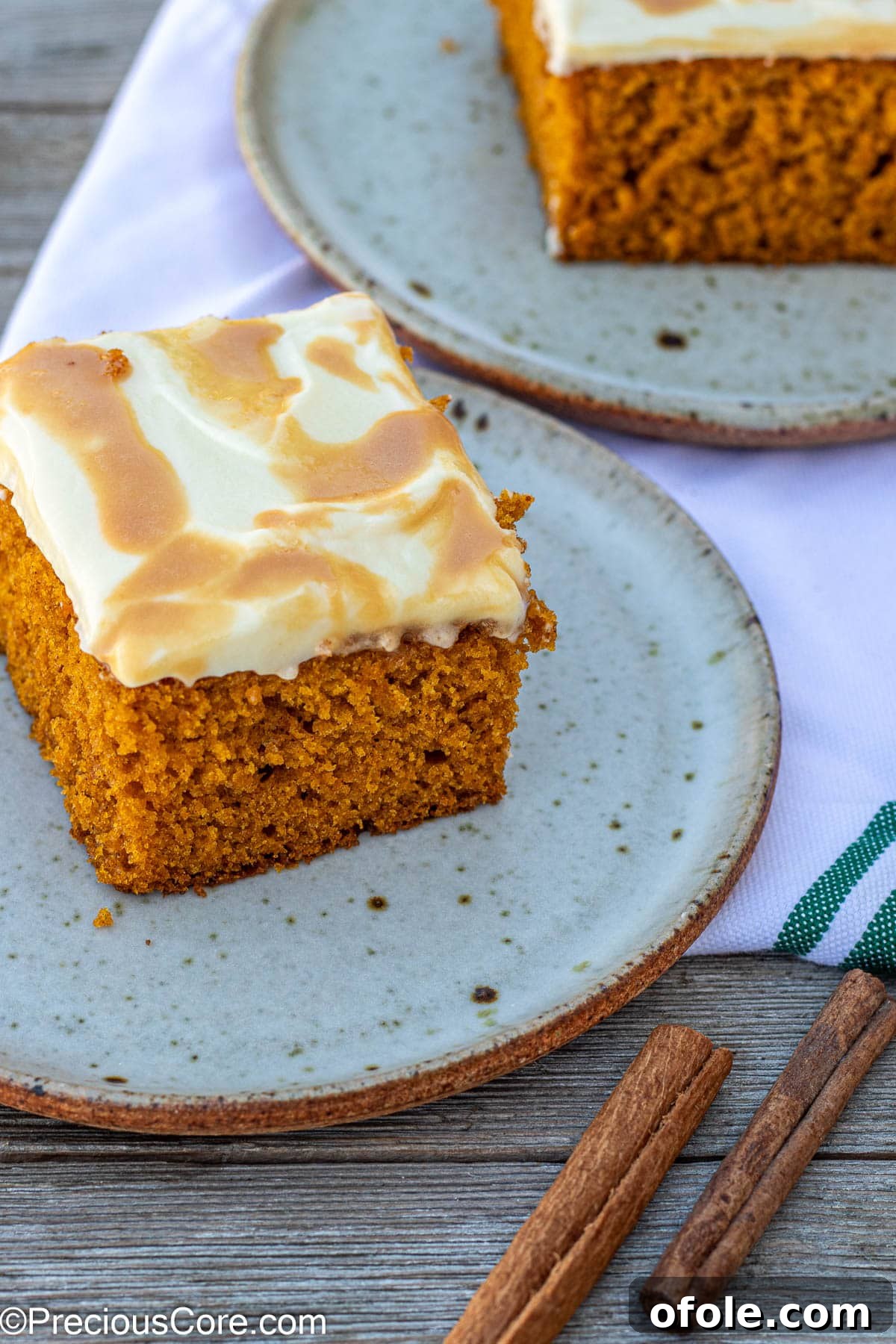 Spiced Pumpkin Cake with Luscious Cream Cheese Frosting 10 Individual slices of pumpkin cake with cream cheese frosting and caramel drizzle on small white plates.