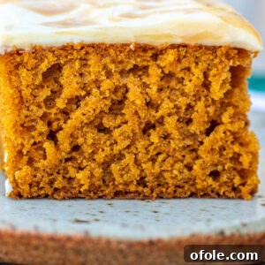Spiced Pumpkin Cake with Luscious Cream Cheese Frosting 11 A tall slice of moist pumpkin cake with thick cream cheese frosting and a drizzle of caramel.