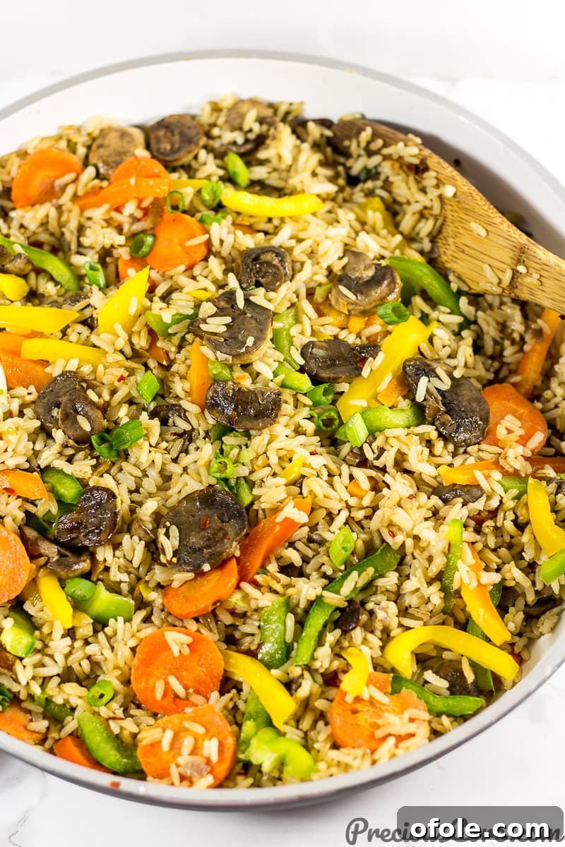 Umami Mushroom Fried Rice 2 A vibrant pan of freshly cooked mushroom fried rice, showcasing rich brown rice, sliced mushrooms, colorful bell peppers, and carrots.