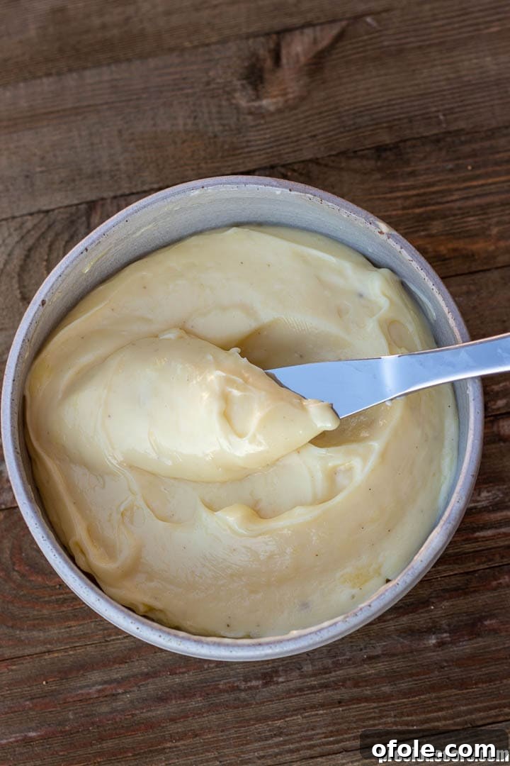 Mastering Homemade Mayonnaise 8 A bowl of freshly made mayonnaise, a butter knife lifting up some mayonnaise.