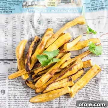 Crispy plantain fries served on a piece of newspaper for a rustic presentation.