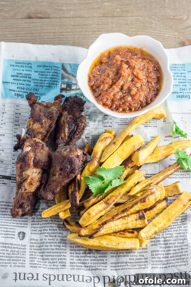 Plantain Fries 4 Baked plantain fries and crispy chicken wings served on a rustic serving paper, ready to be enjoyed.