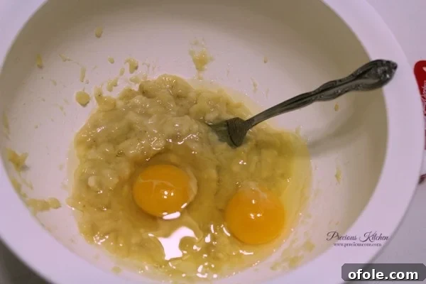 Add Eggs Adding eggs to mashed bananas for pancakes