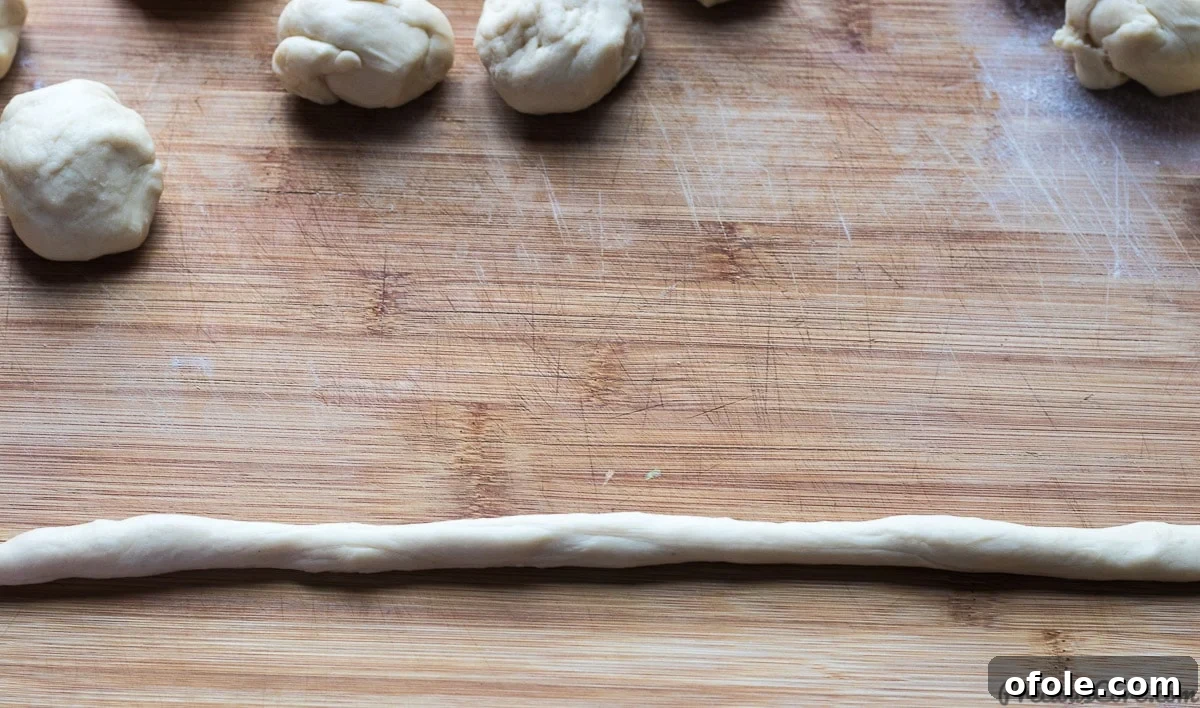 Hands demonstrating how to roll dough into a rope for twisting.