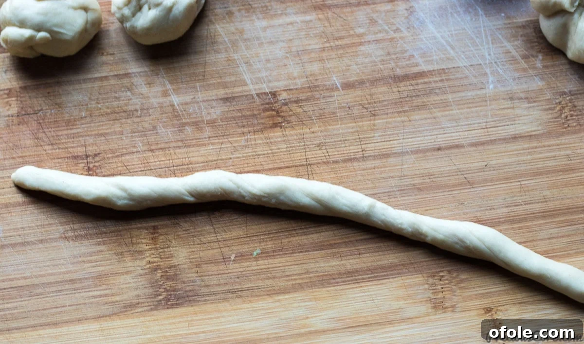 Close-up of dough being twisted by hands to form a doughnut shape.