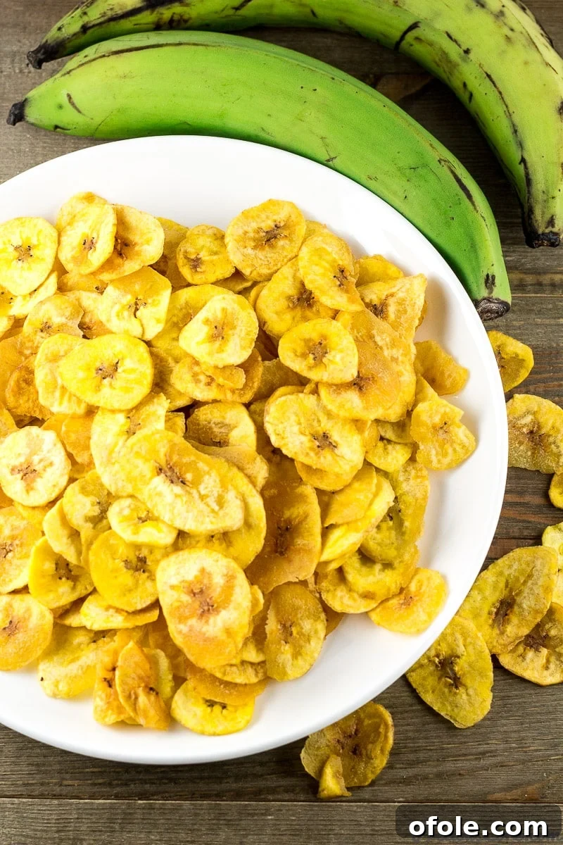The Secret to Perfectly Crispy Plantain Chips 4 Close-up of golden, crispy homemade plantain chips on a white plate, ready to be served.
