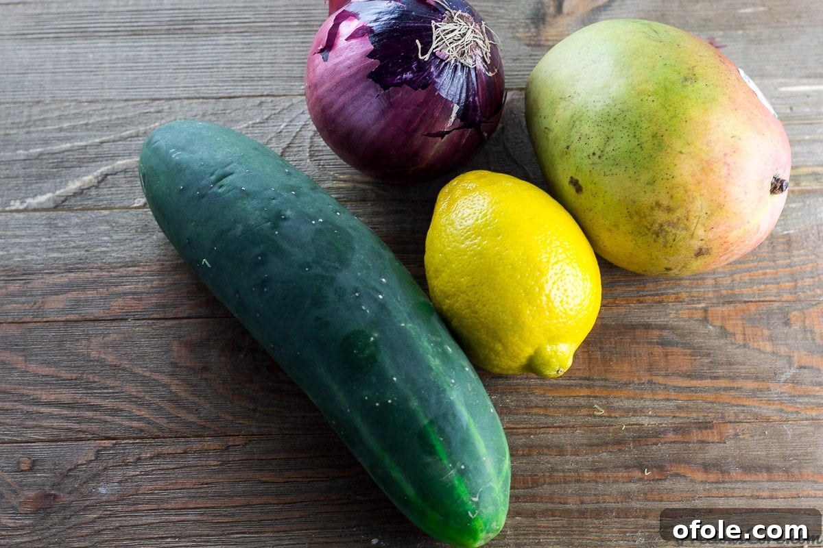 Vibrant Mango Cucumber Refresh 4 Fresh ingredients laid out for Cucumber Mango Salad including cucumber, mango, red onion, and lemon.