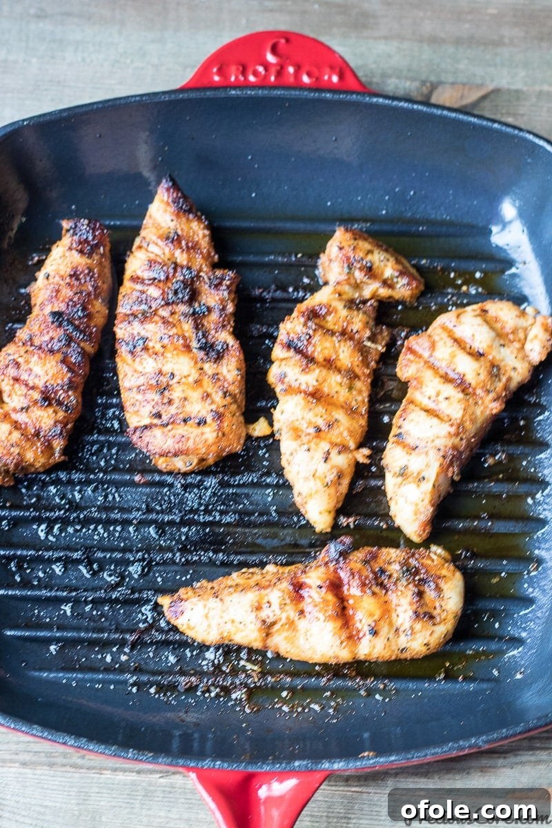 Grilled Chicken Tenders Perfection 4 Close-up of golden brown grilled chicken tenders cooking in a cast iron grill pan on the stovetop