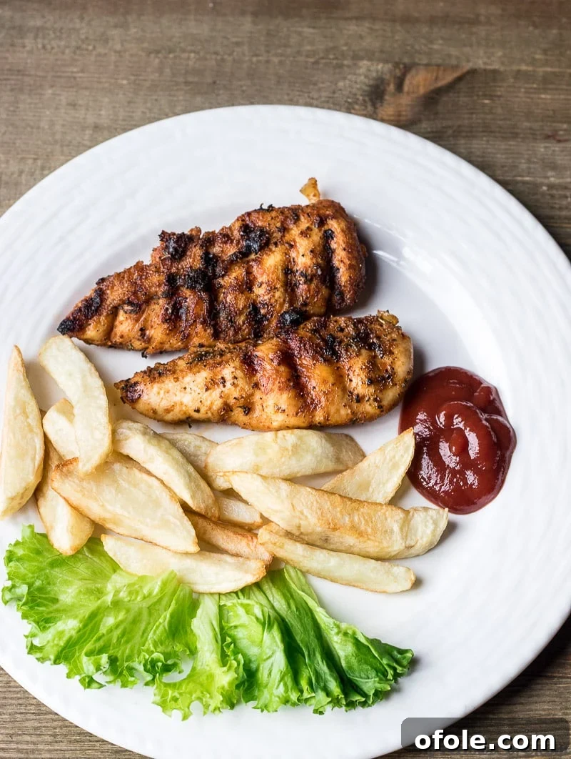 Grilled Chicken Tenders Perfection 6 A plate of delicious grilled chicken tenders served with crispy potato fries and ketchup for a complete meal