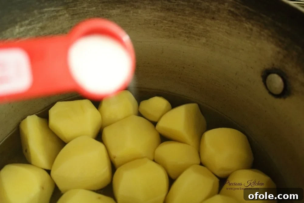 Peeled Irish potatoes boiling in a pot with salt, almost ready for mashing.