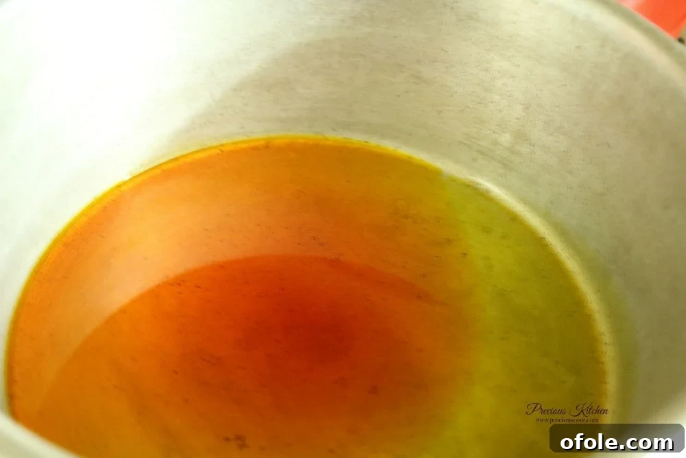 Red palm oil gently heating in a pot, ready for the aromatics.