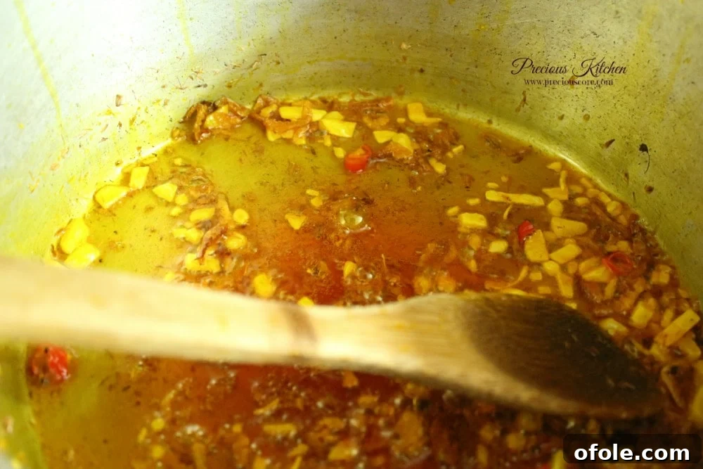 Ground crayfish, chopped pepper, and crumbled Maggi cube cooking with onions in palm oil.