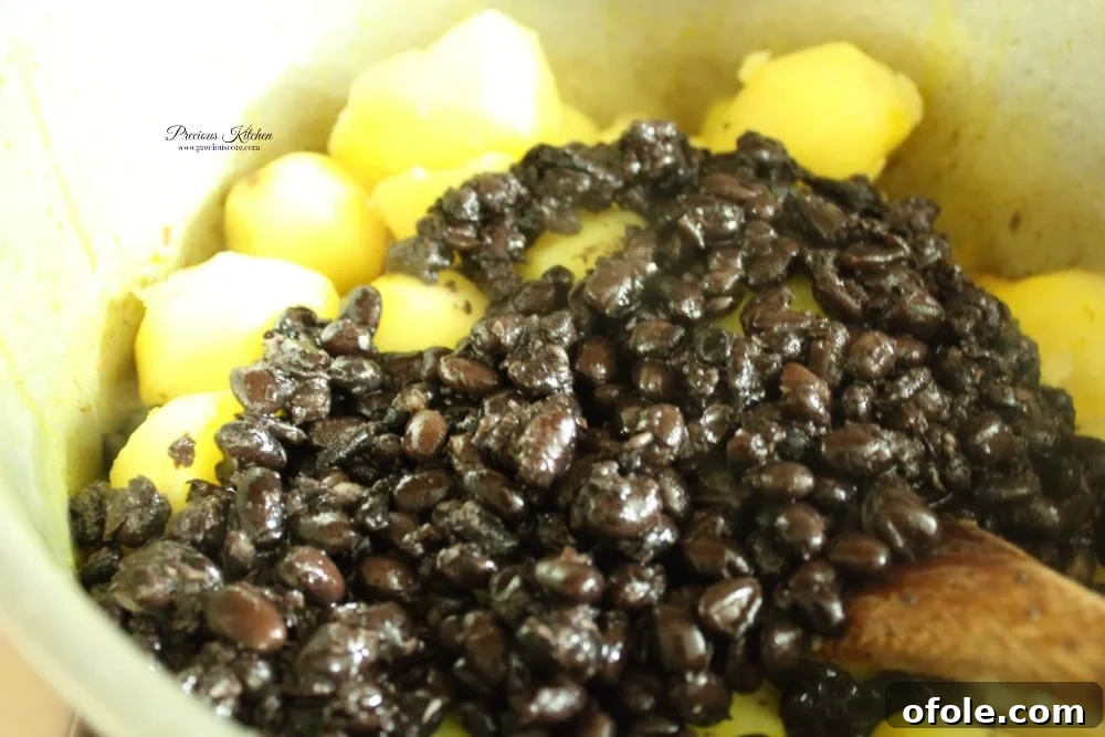 Boiled potatoes and beans added to the flavorful palm oil, onion, and crayfish mixture.