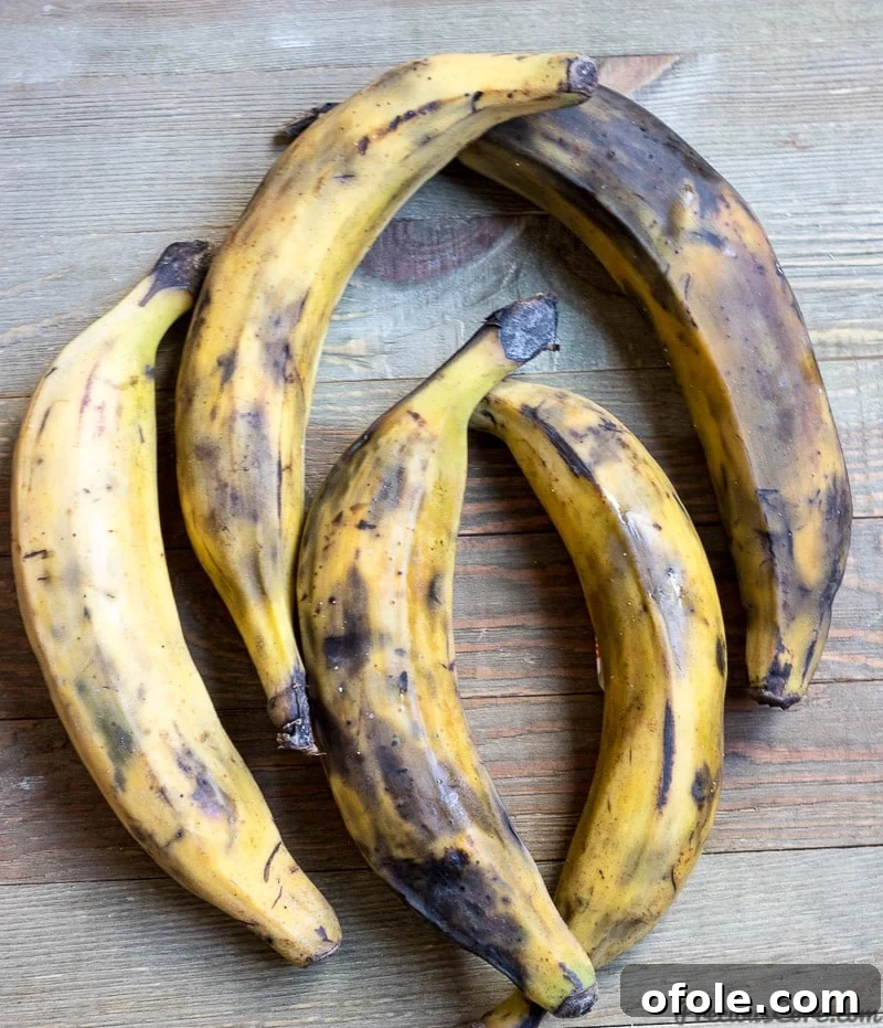 Golden Caramelized Plantains 3 Five vibrant yellow ripe plantains resting on a rustic wooden board, ready for preparation.