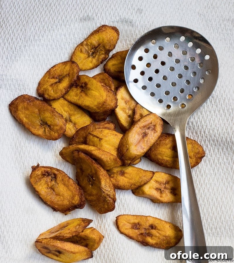 Golden Caramelized Plantains 5 A generous pile of freshly fried, golden-brown sweet plantains resting on paper towels, ready to be served.