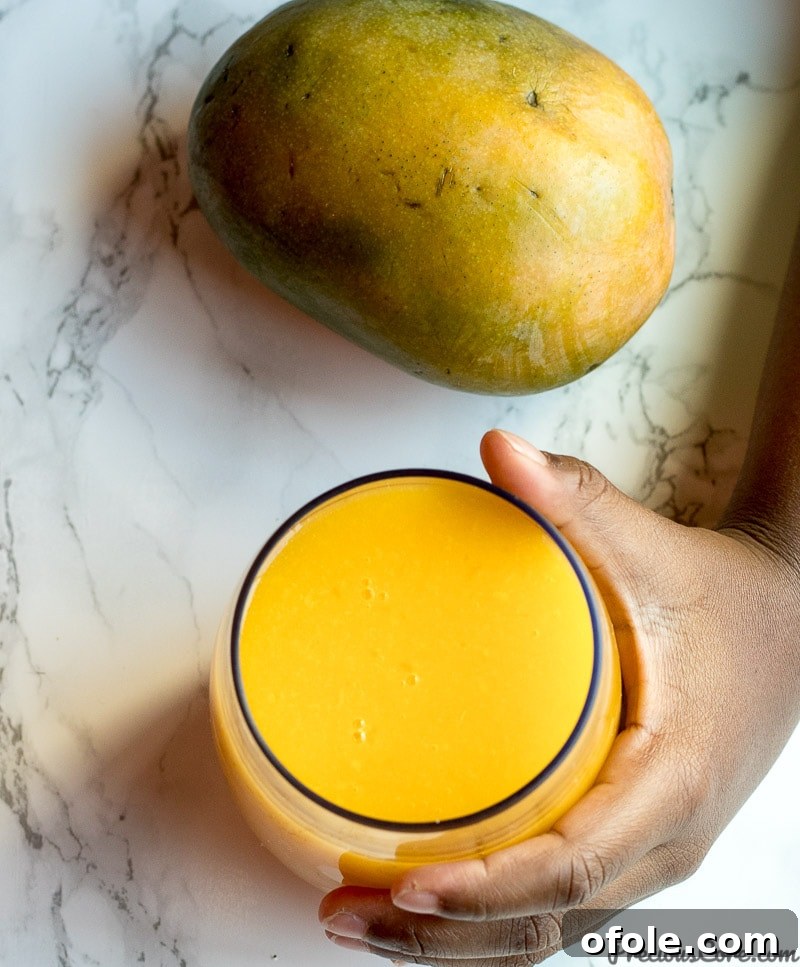 Golden Mango Elixir 3 Close-up of freshly prepared homemade mango juice in a glass, garnished with a mango slice.