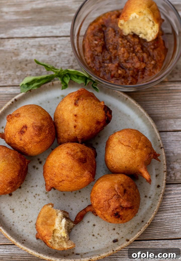 Golden Banana Bites 11 Banana Fritters elegantly plated and served alongside a small bowl of spicy African pepper sauce.