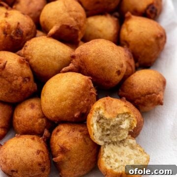 Delicious banana fritters on a platter with one opened up to show its fluffy texture