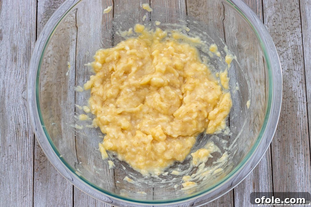 Golden Banana Bites 6 Close-up of mashed bananas in a stainless steel mixing bowl, ready for other ingredients.