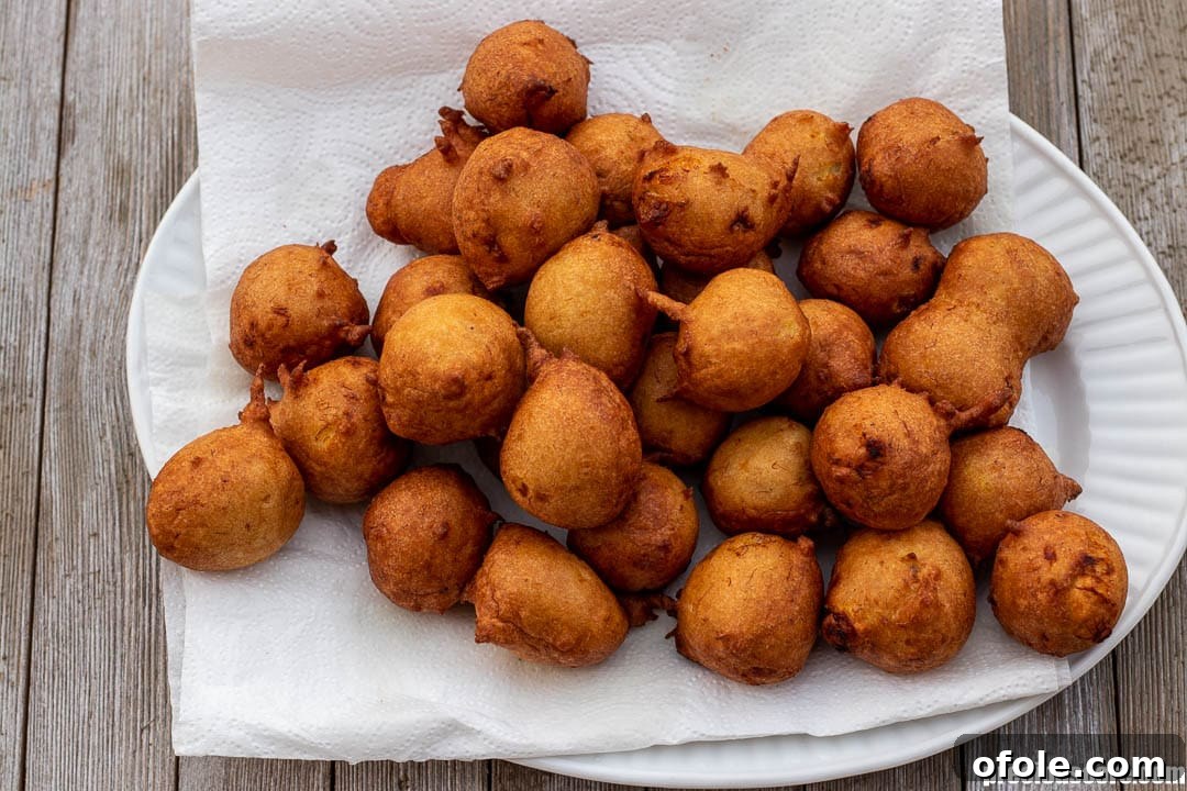 Golden Banana Bites 9 Freshly fried banana fritters resting on a bed of paper towels to drain excess oil.