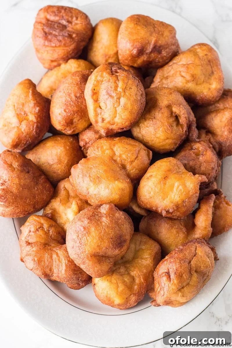 Golden Banana Bites 10 A beautiful display of brown banana fritters arranged on a white serving platter, ready to be enjoyed.